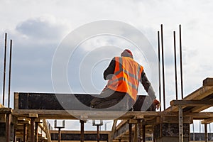 Construction worker assembles concrete formwork in a multi-storey new building. Background