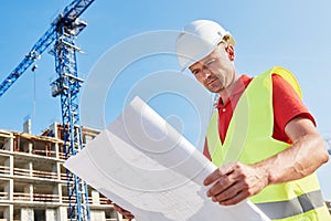 Construction worker with blueprint at building area