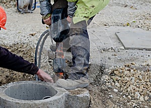 Construction worker breaking concrete around road gully using hydraulic breakers during road works on  housing development photo