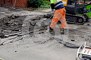 Construction worker breaking road gully using hydraulic breacker during road works on housing development construction site photo
