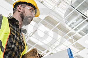 Construction Worker with Building Documentation Inside a Warehouse