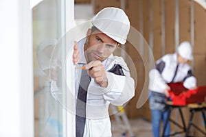 Construction worker building new house and fitting window