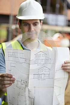 Construction Worker On Building Site Looking At House Plans