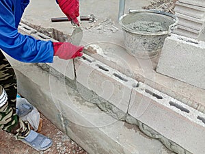 Construction worker is building wall by cement block closeup in construction site.