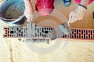 Construction worker building walls and fixing bricks with mortar and putty knife