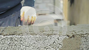 Construction worker builds brick wall, closeup view at construction site