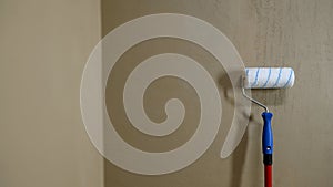 Worker preparing to paint a concrete wall with a roller