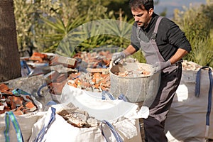 Construction worker carrying carrycot with debris
