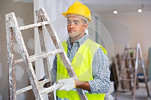 Construction worker carrying stepladder in apartment