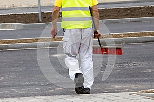 Construction worker carrying sweeping brush