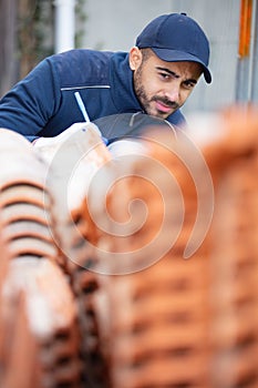 construction worker checking roof tiles for installation