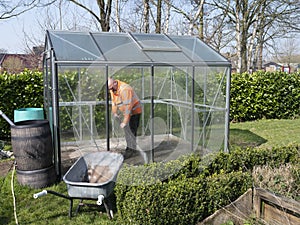 Construction worker cleaning filth with high pressure cleaner from a glass greenhouse