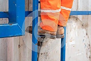 A construction worker is climbing on the platform ladder.