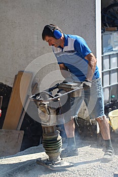 Construction worker compacting soil using compactor. Work with tamping machine