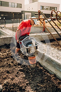 Construction worker compacting soil with vibration compaction machinery