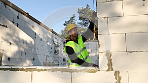 Construction worker at construction site measures the length of the window opening and the wall with tape measure. Cottage are mad