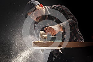 Carpenter slashes the board using an electric saw