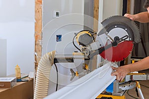 Construction worker cuts wood moldings board on the miter saw