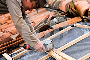 Construction worker cutting with a disc-maker a wood cleat for the implementation of the infrastructure supporting the tiles