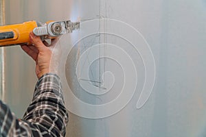 Construction worker cutting gypsum plasterboard by using electric cutter angle grinder