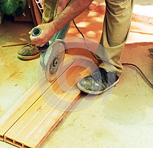 Construction worker cutting large ceramic bricks with electric cutter