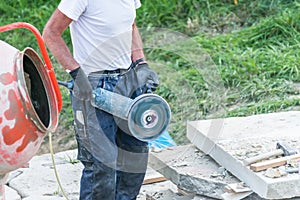 Construction worker is cutting a stone plate with a power cut