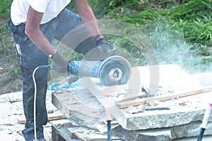 Construction worker is cutting a stone plate with a power cut