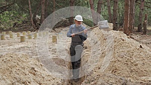 Construction Worker Digging Trench in a Forested Area During Daytime