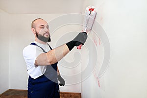 Construction worker doing finish renovation at apartment. Painter contractor using white paint roller brush painting of wall.