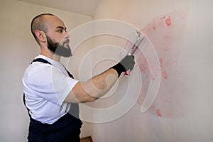 Construction worker doing finish renovation at apartment. Painter contractor using white paint roller brush painting of wall.