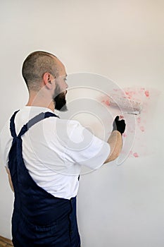 Construction worker doing finish renovation at apartment. Painter contractor using white paint roller brush painting of wall room.