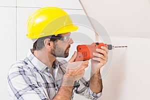 Construction worker drilling hole in wall