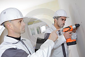 construction worker drilling hole in wall at construction site