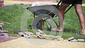 Construction worker is driving a wheelbarrow with paving stones on a construction site. Slow Motion