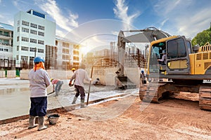 A construction worker with excavator heavy machine and cement truck for control a pouring concrete pump at building construction