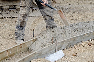 Construction worker filling formwork with wet concrete using shovel