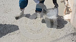 Construction worker finishes pouring concrete floor by troweling the cement