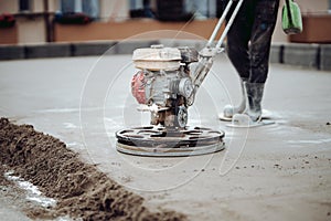 Construction worker finishing concrete screed with power trowel machine. Industrial tools - helicopter concrete screed  finishing