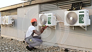 Construction worker fixing conditioner with drill outdoor