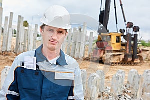 Construction worker foreman in front of pile driver machine