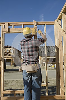 Construction Worker Hammering Nail On Timber Frame