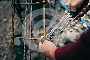 Construction worker - hands securing steel bars with wire rod for reinforcement of concrete