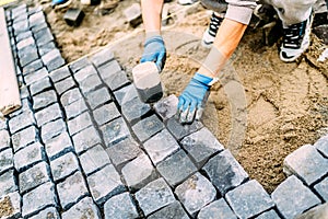 construction worker, handyman using cobblestone granite stones for creating walking path. Terrace or sidewalk details