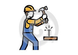 Construction Worker in Hard Hat and Overalls Hammering a Nail Into Wood