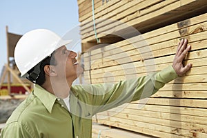 Construction Worker In Hardhat Inspecting Lumber photo