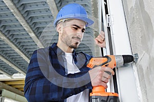 construction worker in helmet uses electric screwdriver