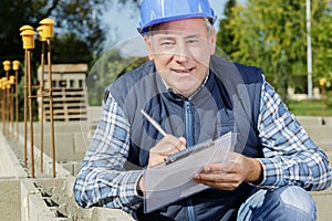 construction worker in helmet writing on clipboard