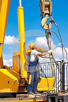 Construction worker during hoisting works by a mobile crane photo