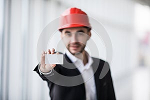 Construction worker holding blank business card in building construction.