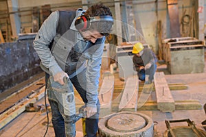 Construction worker holding jackhammer and breaking reinforced concrete